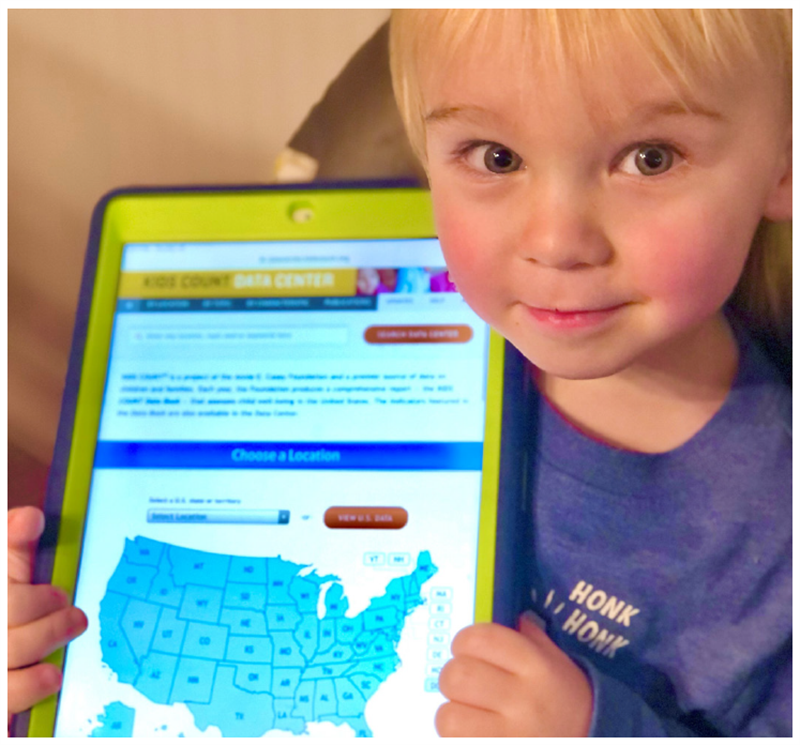Young child showing tablet with data center home page displayed- www.datacenter.kidscount.org