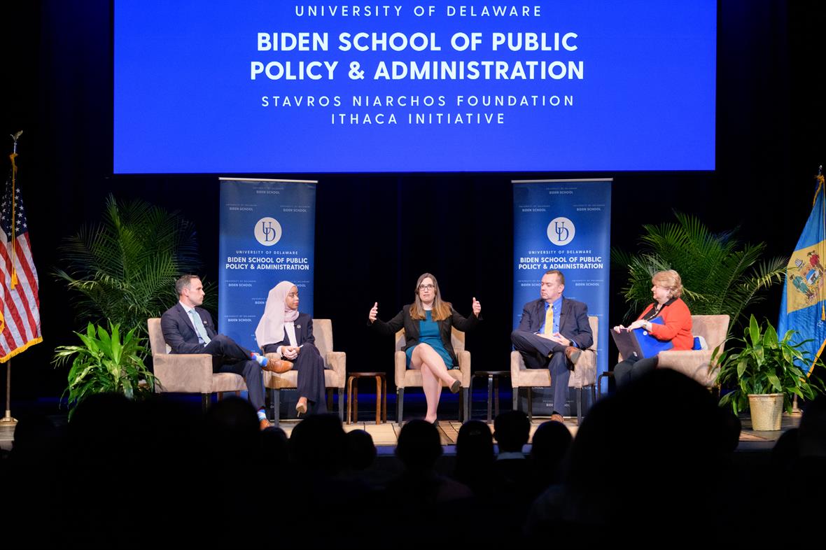 Five seated panelists on a stage in front of a University of Delaware Biden School of Public Policy and Administration Stavros Niarchos Foundation Ithaca Initiative sign.