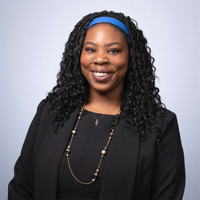 Calaia S. Jackson headshot, pictured in a black top and blazer with a blue headband.