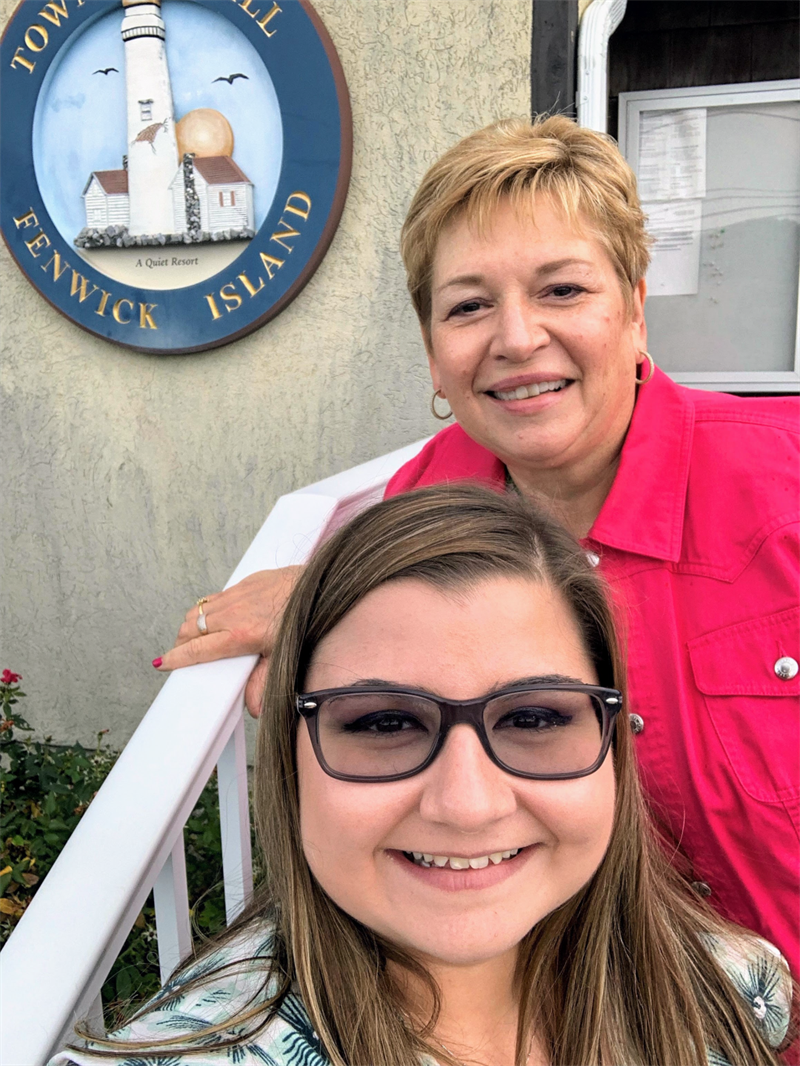 Terry Tieman and Antonina Tantillo stand on the stairs in front of the Town Hall emblem for the Town of Fenwick Island.