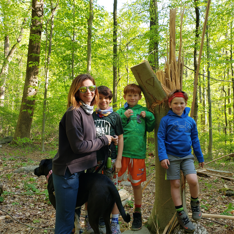 Martha Narvaez with her three sons and dog hiking in the woods.