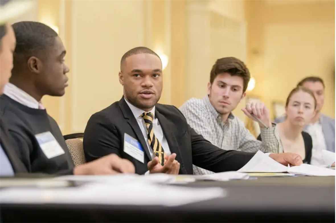 Students seated at a table talking during a breakout session.
