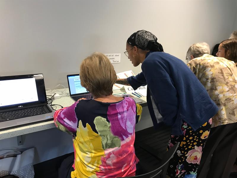 Several event attendees are guided through the technical details of Sussex County's Smart911 systems with the help of IPA student Sade Bruce.
