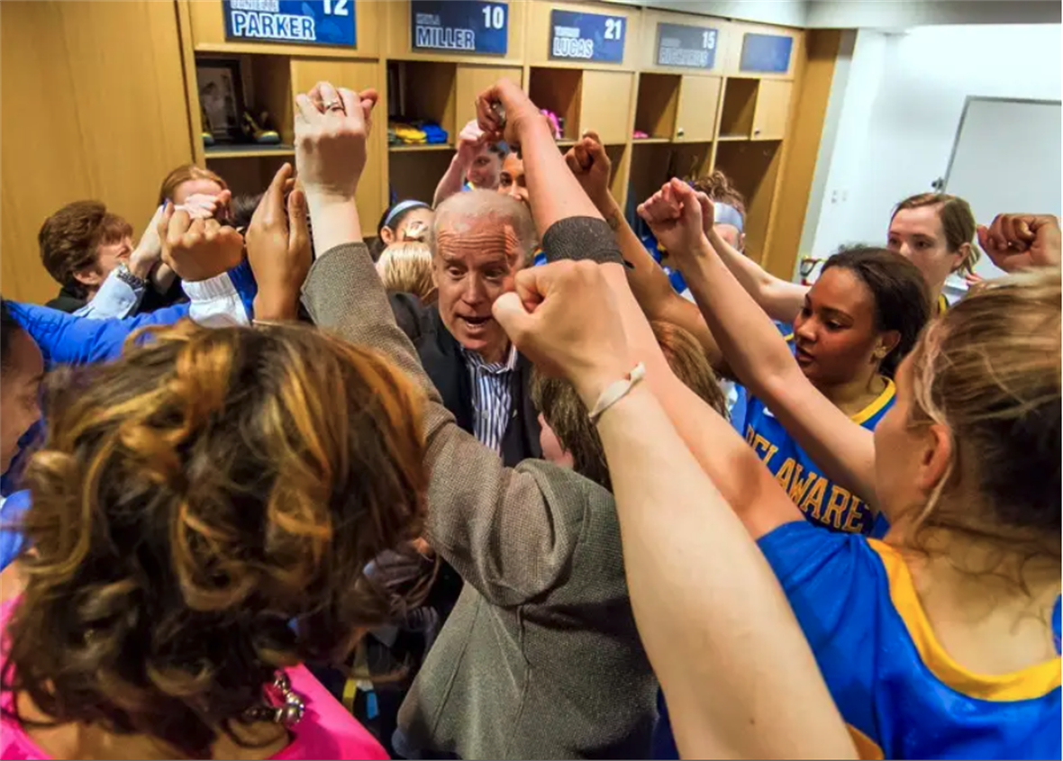 Joe Biden with the UD women's basketball team with their fists in the air.