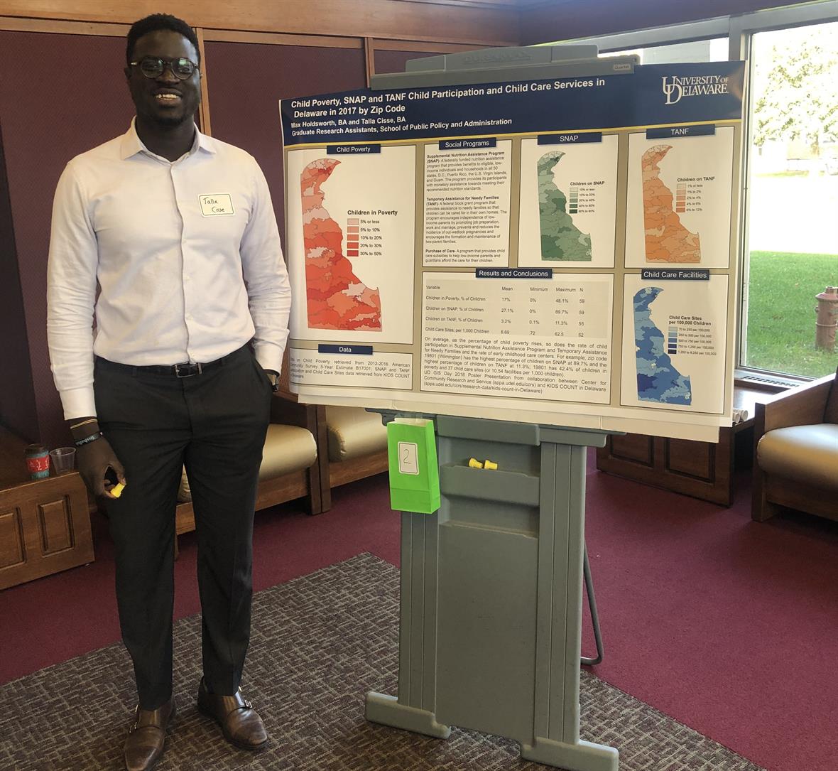 Talla Cisse standing besides the winning map poster at GIS Day