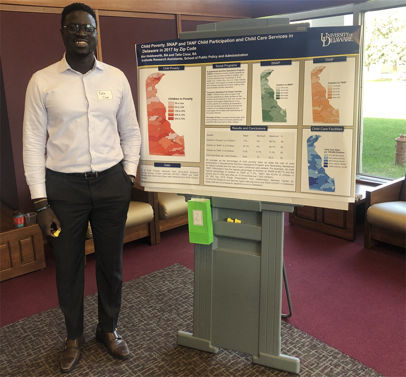 Talla Cisse, stands besides their team's winning poster at UD GIS Day, 2018