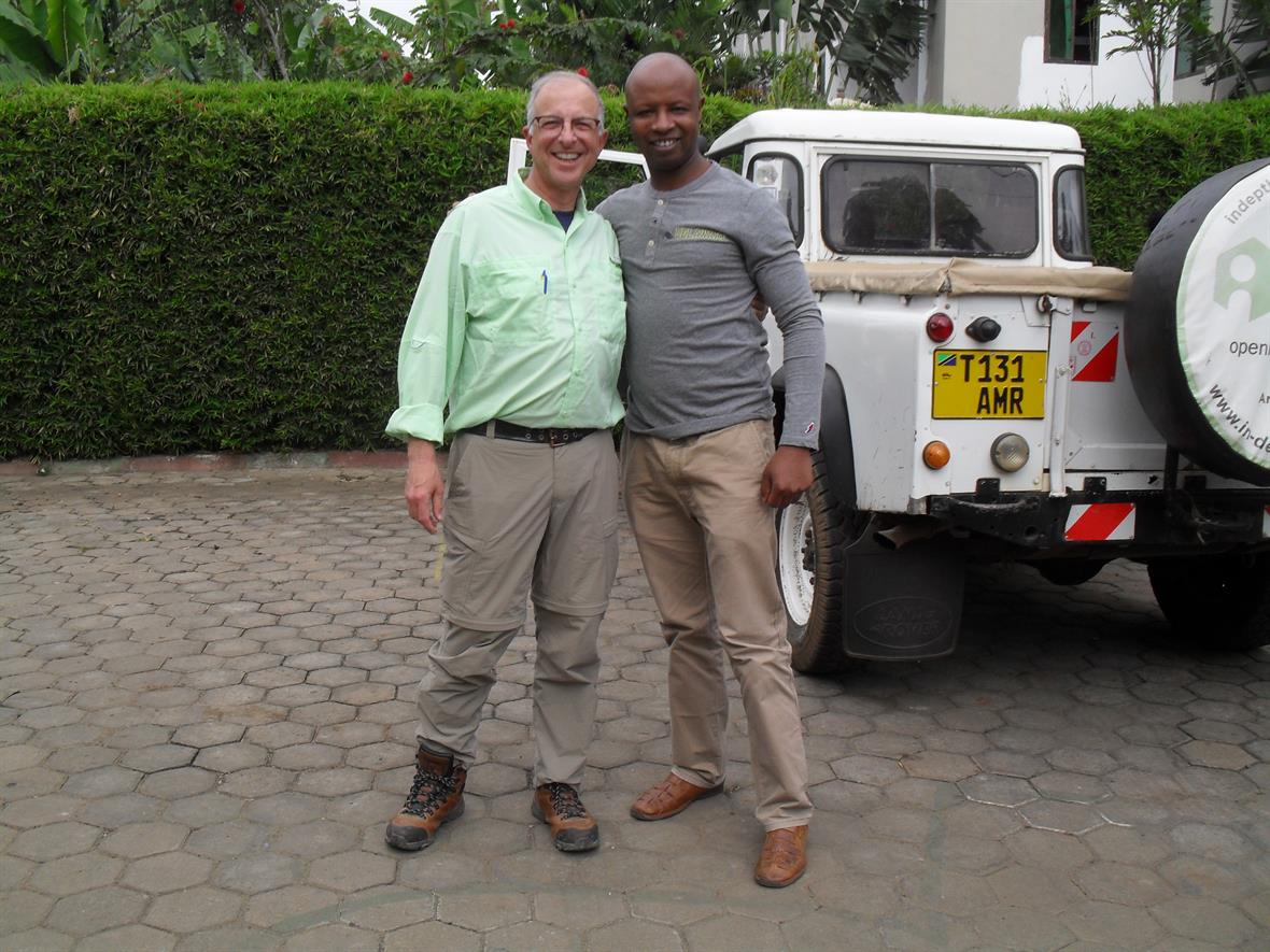 Two men pose in front of a white truck.