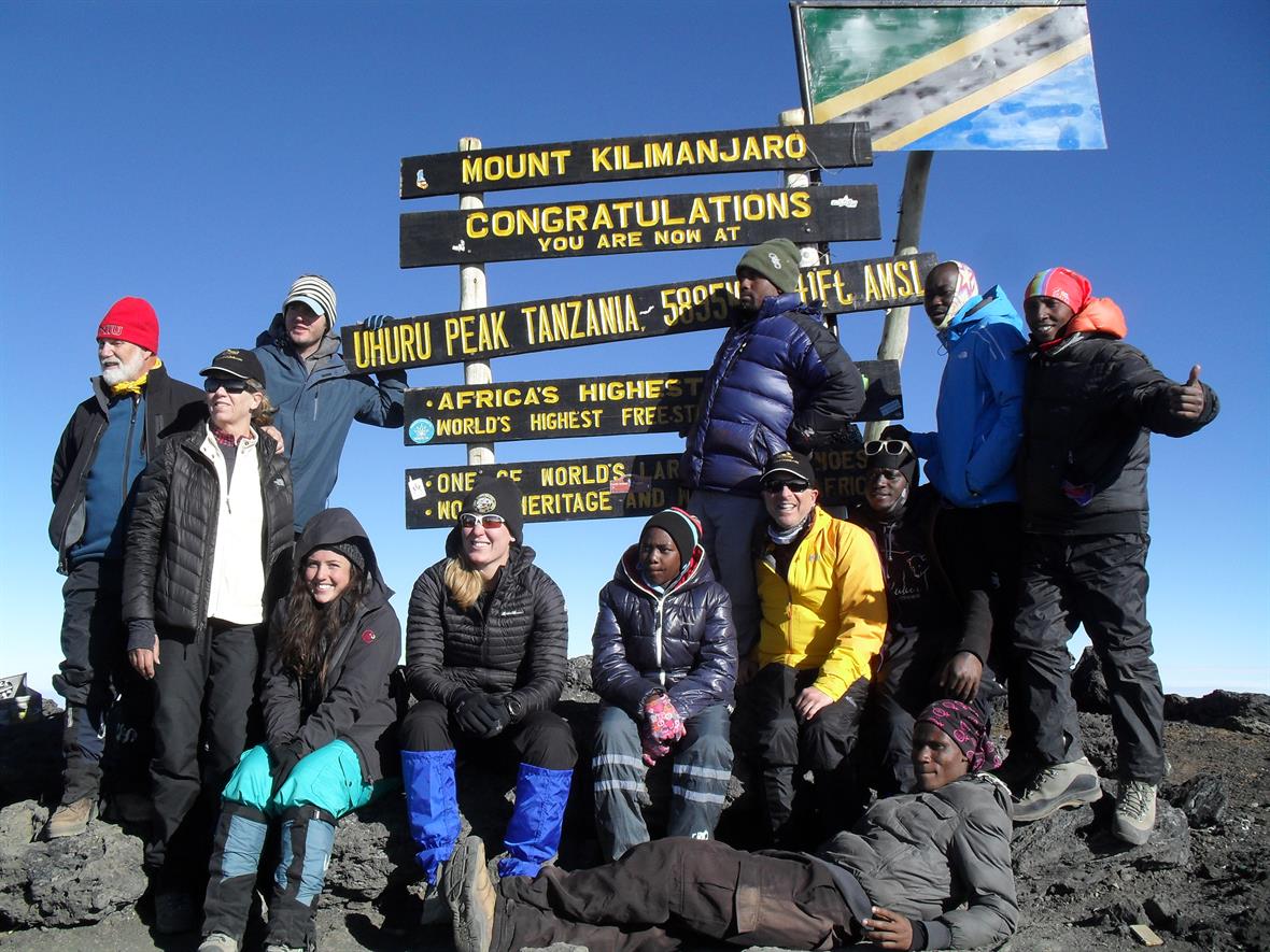 A group of 12 people pose at the summit of Mt. Kiliminjaro.