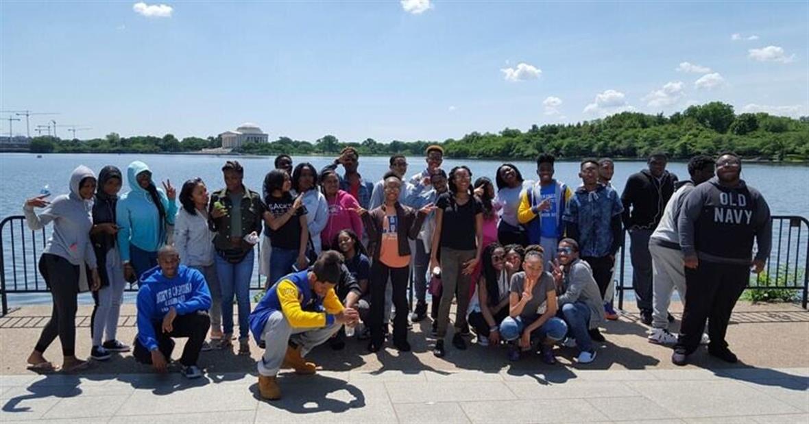 Thirty mentees stand along the Potomac River in Washington, DC, with the Jefferson Memorial in the background.