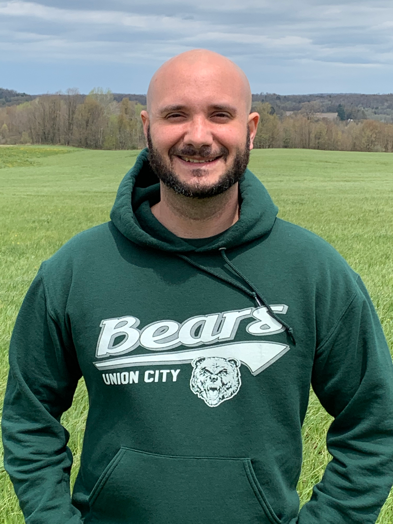 Chris Kelly stands outside overlooking the hills of Pennsyvania, wearing a Union City Bears sweatshirt.