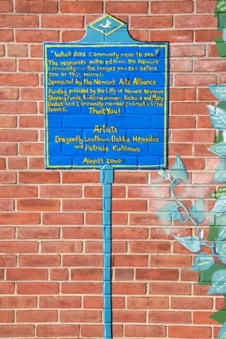 Part of a painted mural on the side of a brick building looks like a historal plaque. 