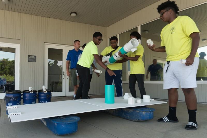 Marine Advisory Service specialist Ed Hale (left) and Jerimiah Wise (right) look on as some of Jerimiahs fellow Green Jobs participants  Zakir Moore, Daniah Righter (hidden), Roberto Nu??ez and Anthony Lewis (left to right)  begin to assemble a Floating Upweller System, or FLUPSY, for Delaware Sea Grants oyster aquaculture demonstration project.