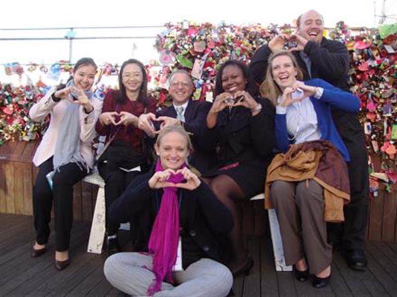 A group of students studying abroad in Seoul make hearts with their hands.